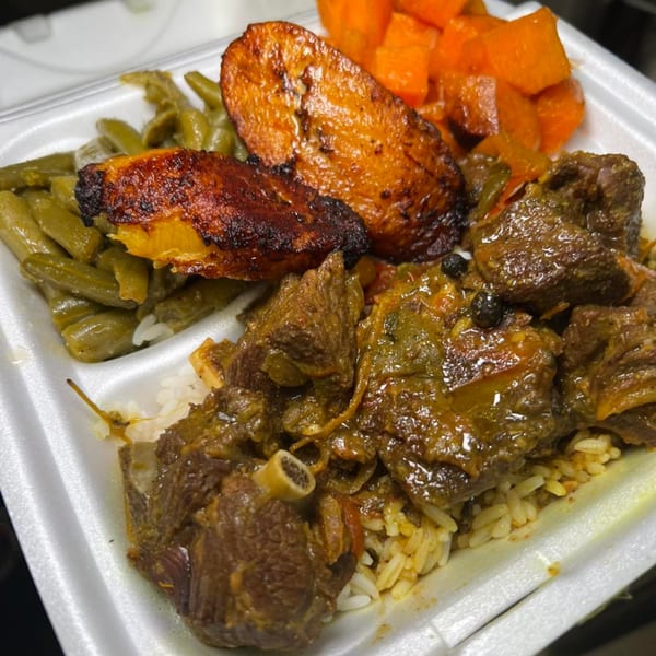 Soul food meal with stewed meat, rice, green beans, fried plantains, and sweet potatoes in a takeout container.