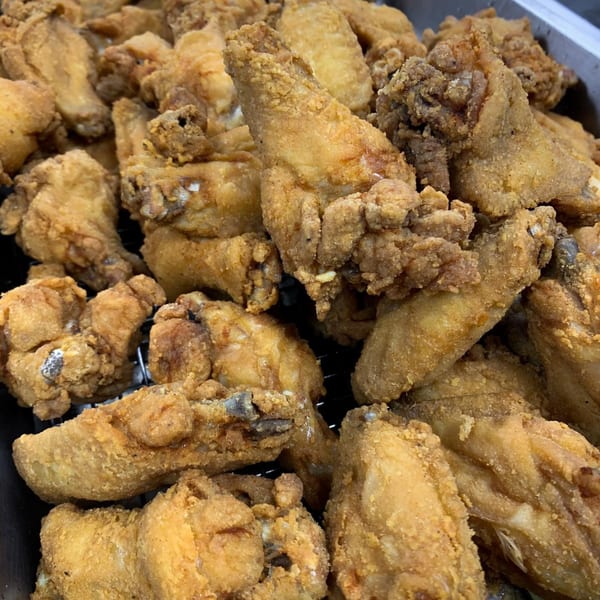 Close-up of a large batch of golden-brown fried chicken pieces, ready to be served.