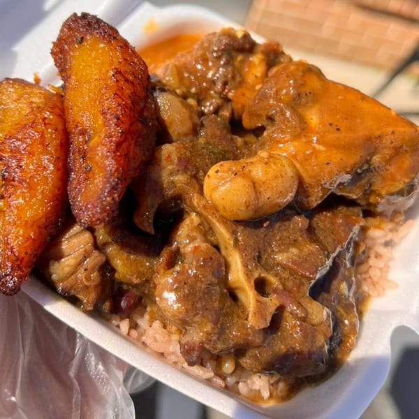 Soul food oxtail and rice with fried plantains in a white takeout container.