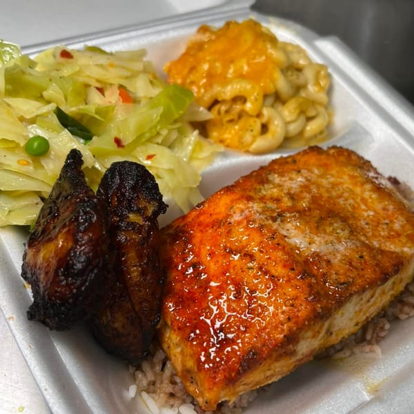 Soul food meal with baked salmon, two dark chicken pieces, cabbage, and macaroni and cheese.